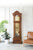 Reloj de pie de madera marrón con esfera de cristal y péndulo dorado en el interior