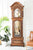 Reloj de pie de madera con caja tallada y esfera visible a través del cristal