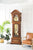 Reloj de pie de madera con estructura curva, mecanismo visible tras cristal