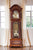 Reloj de pie de madera con frentes ornamentados, vista del péndulo y mecanismo a través de cristal