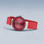 Reloj de mujer con esfera roja, caja de acero inoxidable y correa roja, vista lateral.