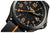 Reloj de hombre primer plano: esfera negra, manecillas naranjas, índices luminiscentes verdes, correa negra