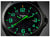 Reloj de hombre en primer plano: logo de traser, esfera negra con números luminosos verdes