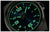 Primer plano de reloj de hombre: esfera negra con manecillas e índices luminosos verdes.