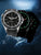 Reloj de hombre con esfera negra y marcadores luminosos verdes, correa de silicona negra