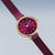 Reloj de mujer con correa de malla metálica violeta, caja redonda en oro rosa y esfera lila.