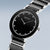 "Reloj de mujer con esfera redonda negra, manecillas plateadas y bisel de cerámica."