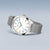 Reloj redondo con esfera blanca, índices de colores y correa de malla metálica plateada
