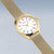 Reloj de pulsera en tono dorado con esfera blanca, marcadores de hora de colores y correa milanesa