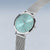 Reloj de mujer, vista frontal, con esfera turquesa, correa de malla plateada y corona