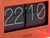 Neonorange Tischuhr mit Klappzahlen-Display im Acrylgehäuse, Nahansicht der Zahlen 22 und 10.