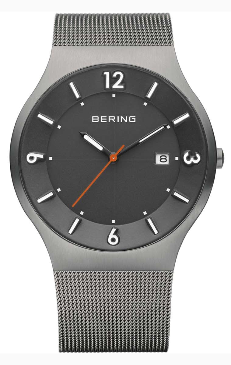 Reloj de hombre con esfera negra, manecillas naranjas y pulsera de malla metálica, caja redonda