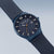 Reloj de hombre con esfera azul y correa de malla metálica, vista lateral de la esfera