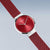 "Reloj de mujer con esfera redonda roja y correa de malla metálica roja, vista en perspectiva"
