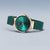 Reloj Bering para mujer de perfil, caja en tono oro rosa, esfera verde esmeralda y correa de Milanesa verde.