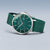 Reloj de hombre llevado en diagonal: esfera verde, caja plateada, correa de malla verde