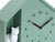 Primer plano de un reloj de pared: carcasa verde menta, números 12-6, manecillas negras y motivo de gato