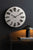 Reloj de pared redondo con esfera clara, manecillas negras y números de clip metálicos