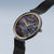 "Reloj de mujer con esfera oscura, manecillas doradas y corona lateral, correa milanesa"