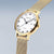 "Reloj de mujer en perfil: esfera blanca con índices, caja dorada, correa de malla"