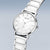 "Reloj de mujer, esfera blanca con índices y marcación solar, brazalete de cerámica plateada."