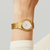 Reloj dorado de mujer en la muñeca con esfera blanca y correa de metal
