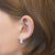Aros con piedras rosas, montura rectangular estrecha en la oreja.