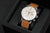 Reloj de hombre con correa de cuero marrón, esfera blanca y funciones de cronógrafo