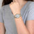 Reloj de mujer en la muñeca con pulsera plateada, detalles dorados y esfera redonda