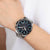 Reloj de hombre en la muñeca: correa de acero inoxidable, esfera negra con índices azules y cronógrafo