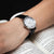 Reloj de mujer en la muñeca con correa de cuero negra y esfera blanca