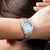 "Reloj de mujer con esfera azul claro y pulsera de acero inoxidable en la muñeca"