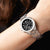Reloj de mujer en la muñeca con esfera negra y correa de acero inoxidable