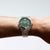 Pulsera de hombre con esfera verde en la muñeca, correa de acero inoxidable