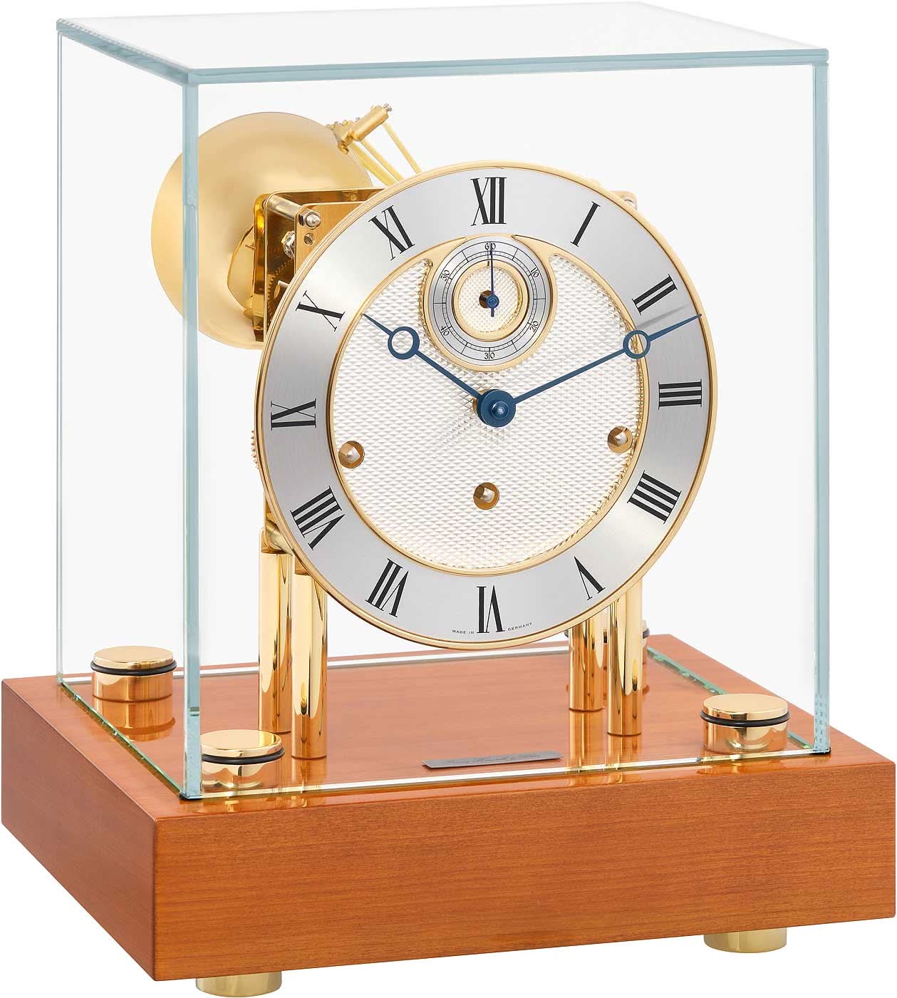 Reloj de mesa con mecanismo visible, esfera redonda y base de madera bajo cristal