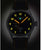Reloj de hombre con correa de cuero negra y caja plateada; esfera oscura con números amarillos