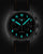 Reloj de hombre con caja oscura, números luminosos azules y correa de cuero negra con costuras