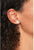 Pendientes redondos con piedra clara, metal plateado, primer plano en la oreja