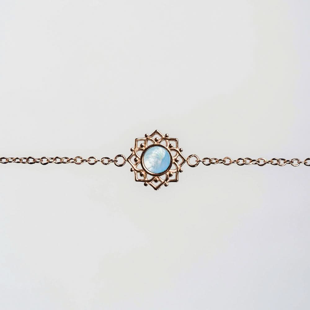 Pulsera en tono cobre con colgante redondo de nácar azul en un marco de filigrana