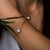 Pulsera dorada en el brazo con colgante redondo de nácar