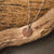 Collar con colgante redondo de madera en cadena de plata sobre rama de madera