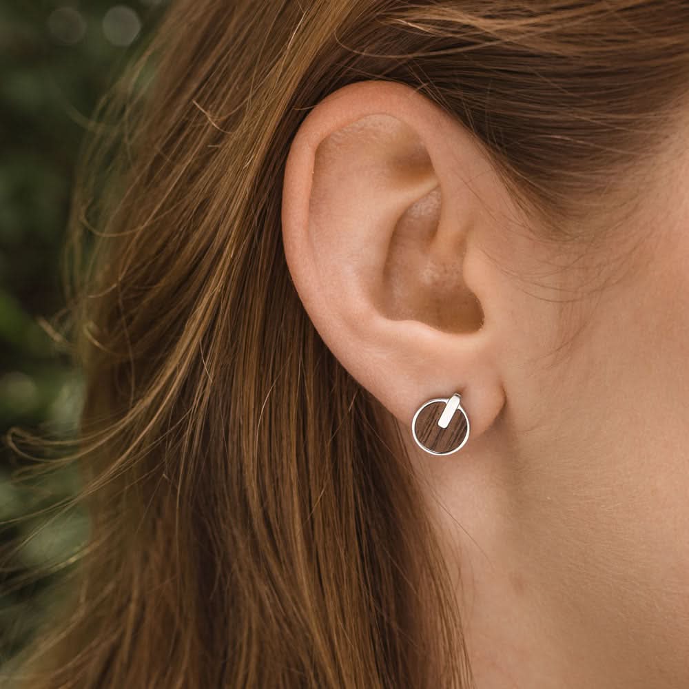 Pendientes redondos de madera con montura plateada y disco de madera en la oreja