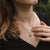 "Collar en el cuello: cadena dorada con colgante redondo de madera sobre top negro"