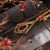 Colgante de gota dorado con marco ornamental cuadrado y piedra roja