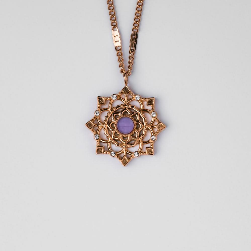 Collar dorado con colgante redondo y piedra violeta en un marco ornamental