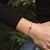 Pulsera en la muñeca con cadena dorada y colgante redondo de madera