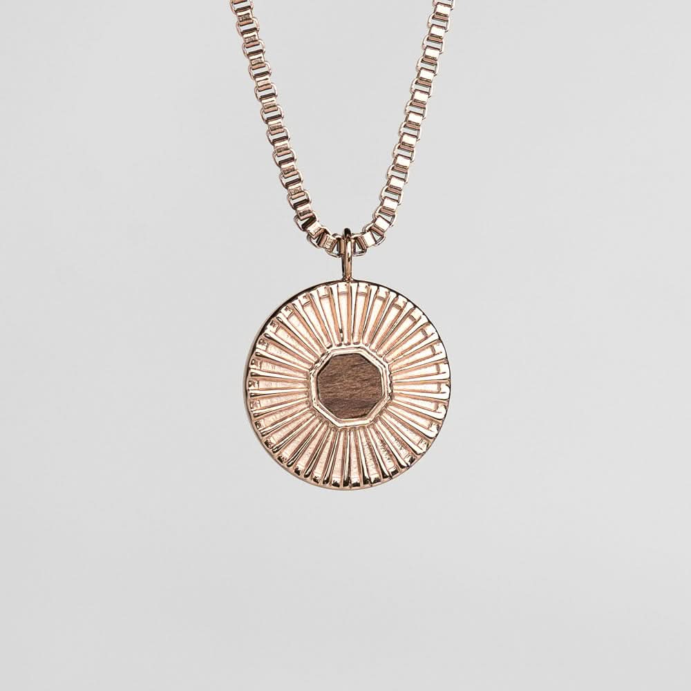 Collar plateado con colgante redondo y fino relieve de rayos.