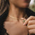 Collar dorado con colgante redondo y piedra verde, cerca del cierre