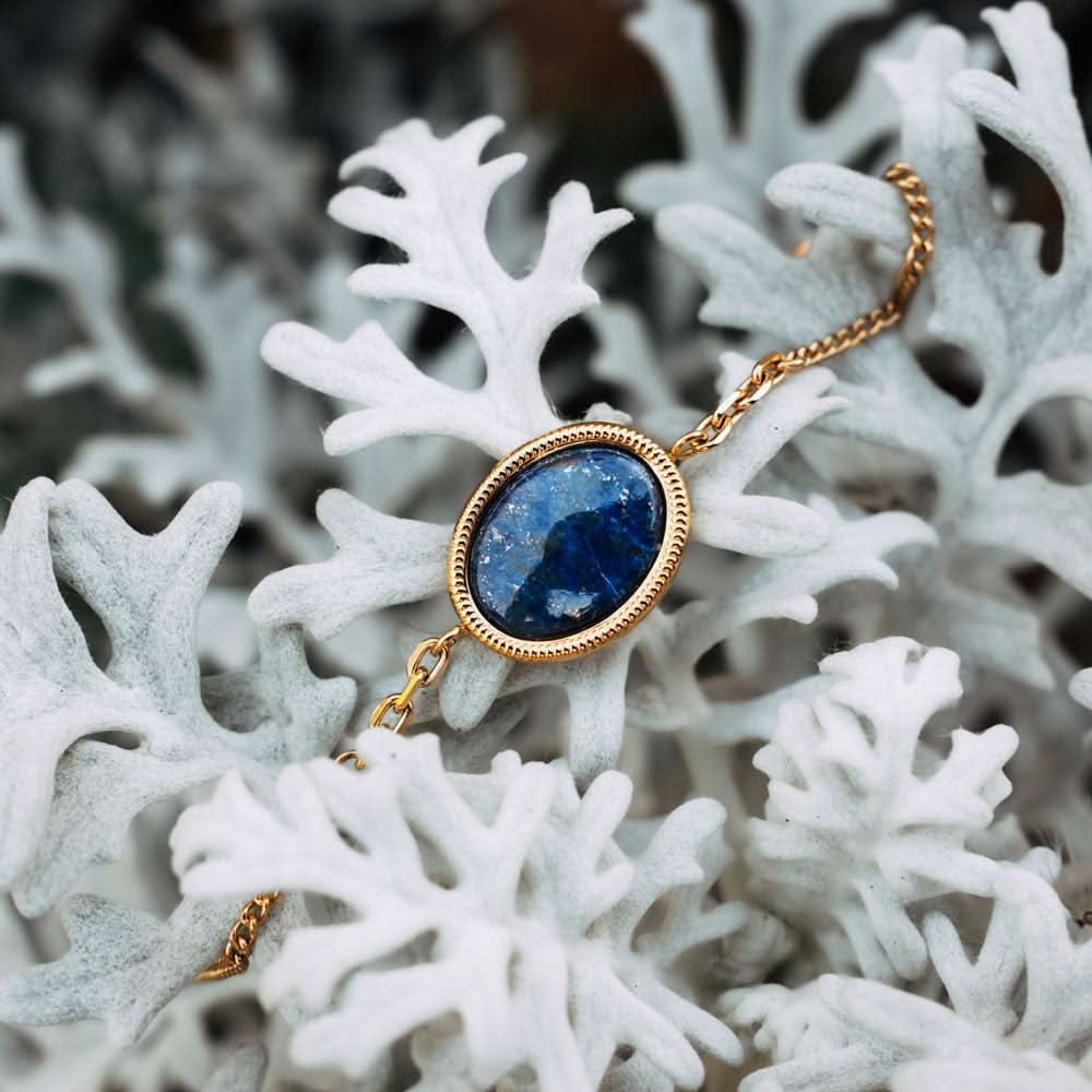Pulsera dorada con colgante ovalado y cabujón azul en pulsera de eslabones