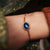 Pulsera dorada con colgante de cabujón ovalado azul en la muñeca